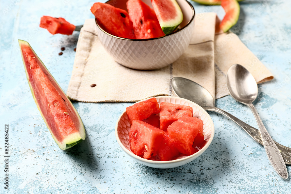 Bowls with pieces of fresh watermelon on blue background