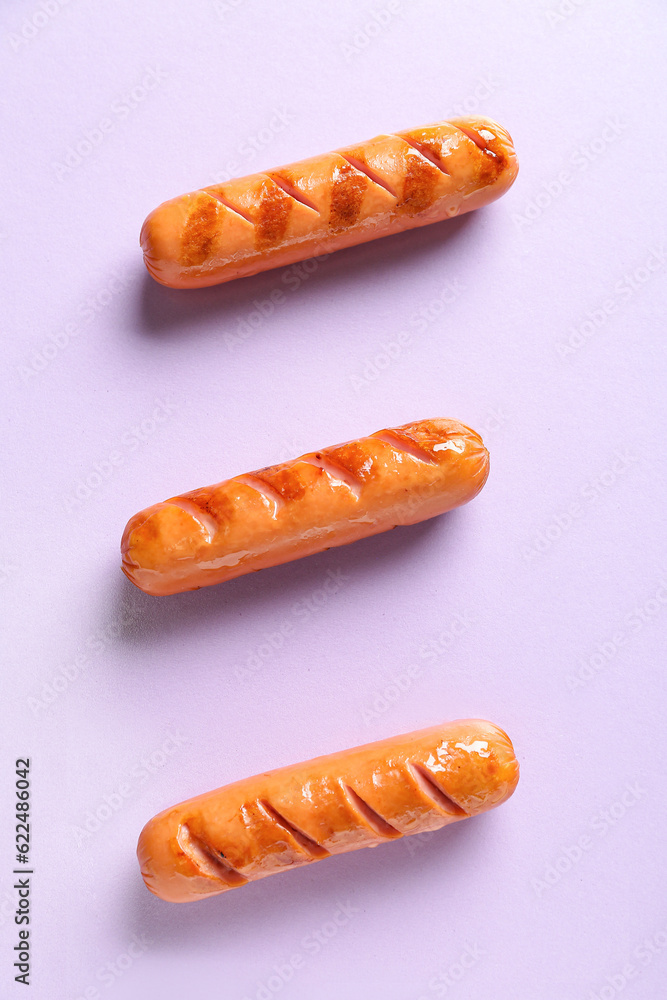 Tasty grilled sausages on lilac background