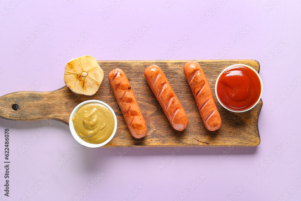 Wooden board with tasty grilled sausages and sauces on lilac background