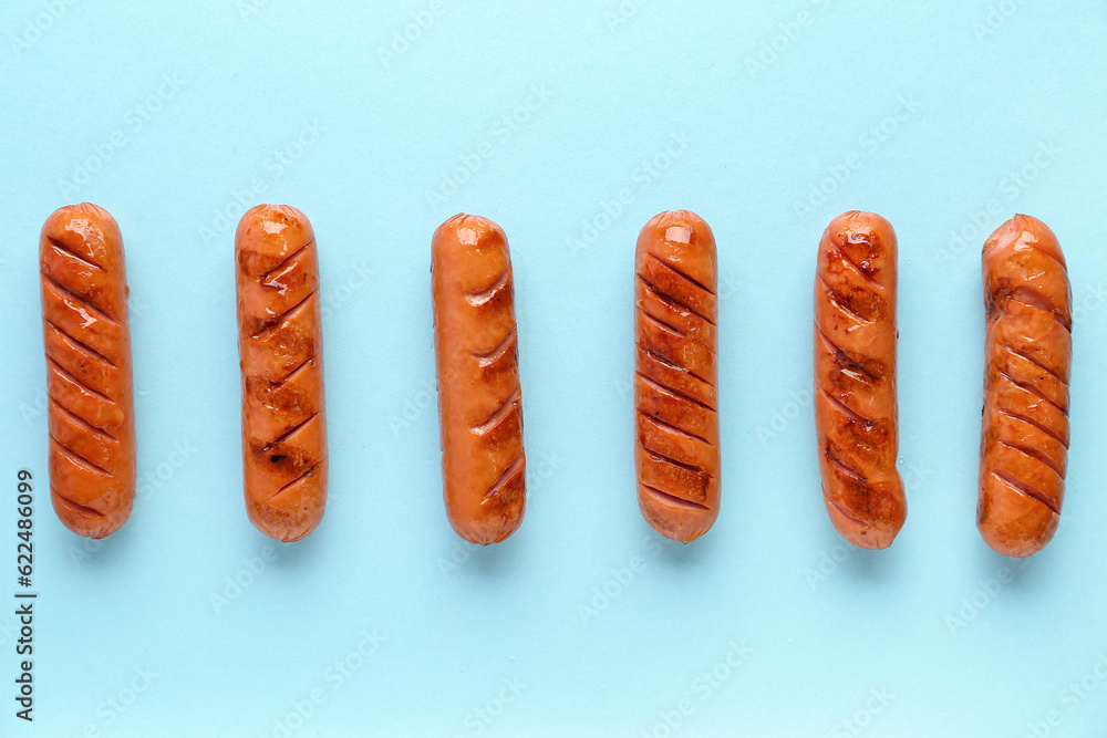 Tasty grilled sausages on blue background