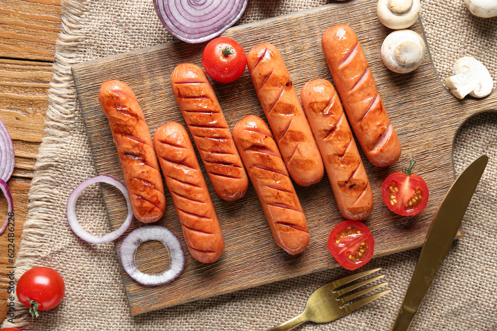 Wooden board with tasty grilled sausages on table