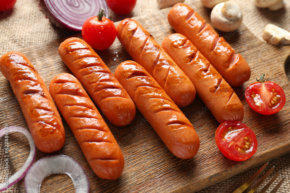 Wooden board with tasty grilled sausages on table