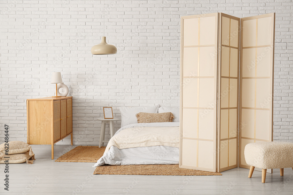 Interior of modern bedroom with cabinet and folding screen