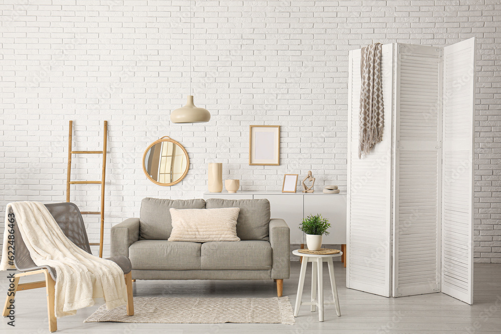 Modern living room interior with grey sofa, armchair and folding screen