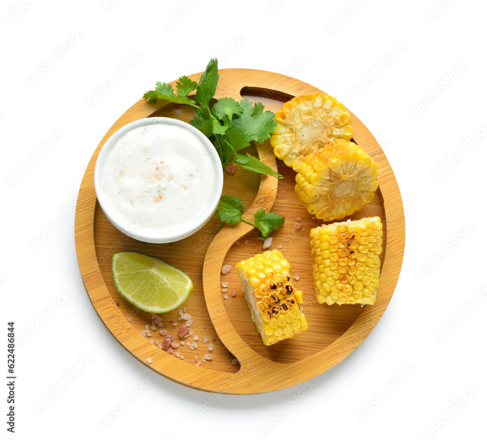 Wooden board with cut tasty grilled corn cob and sauce on white background