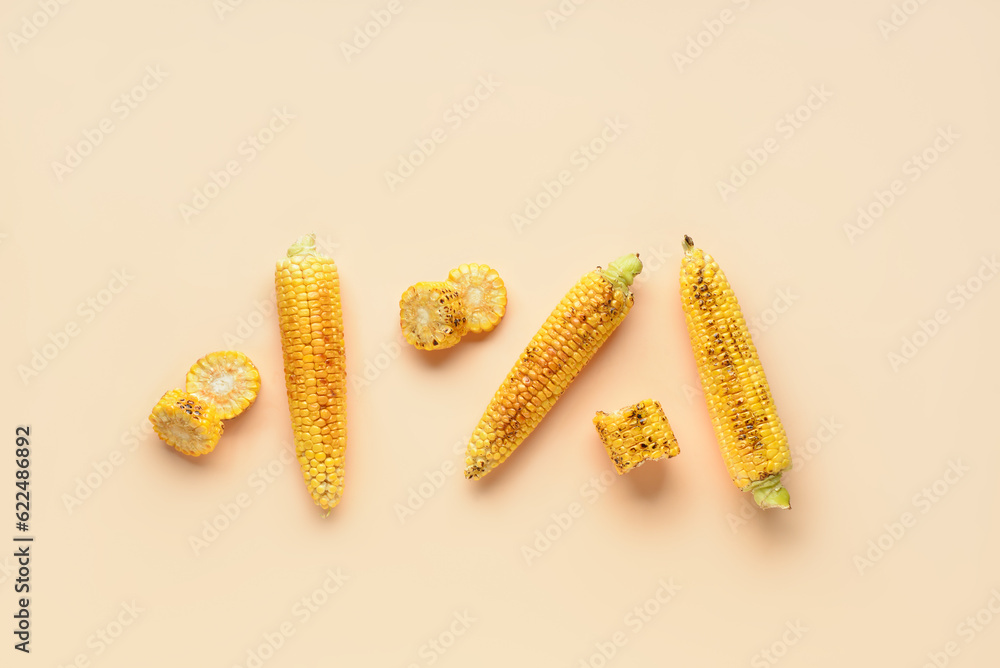 Tasty grilled corn cobs on orange background