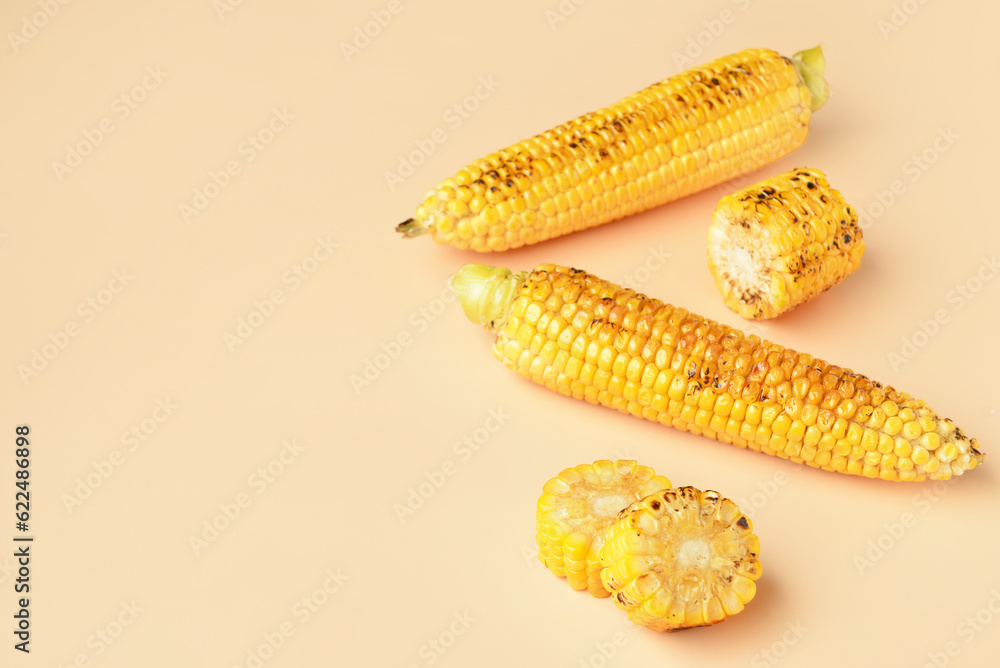 Tasty grilled corn cobs on orange background