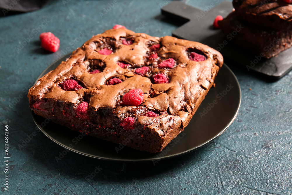 Plate with raspberry chocolate brownie on dark table