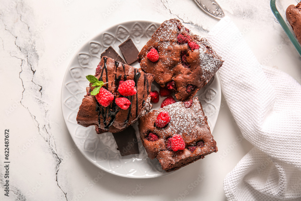 Plate with pieces of raspberry chocolate brownie on white background