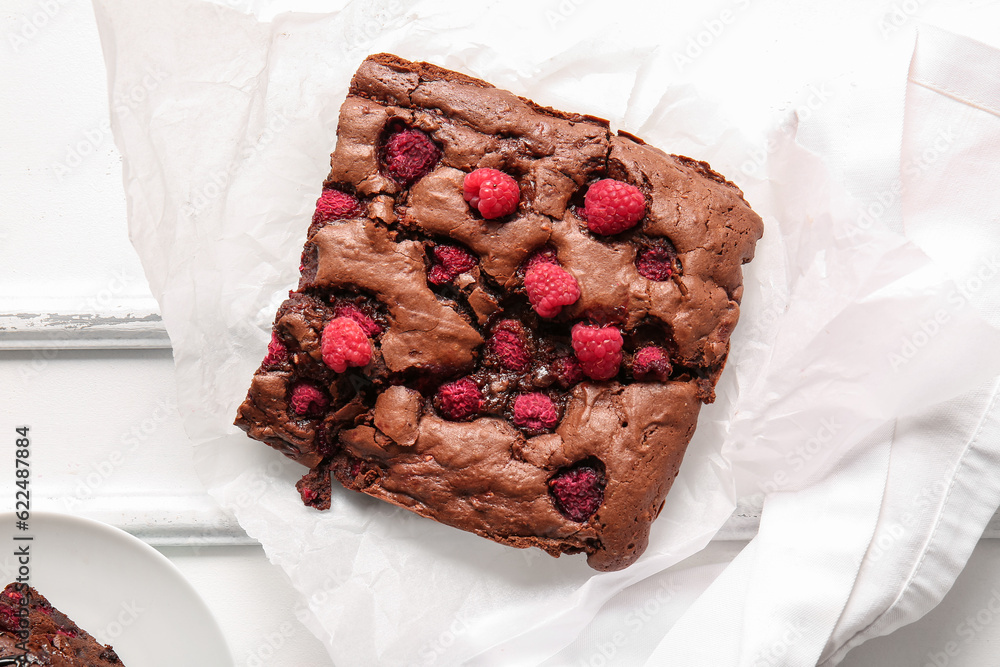 Baking paper with raspberry chocolate brownie on white background