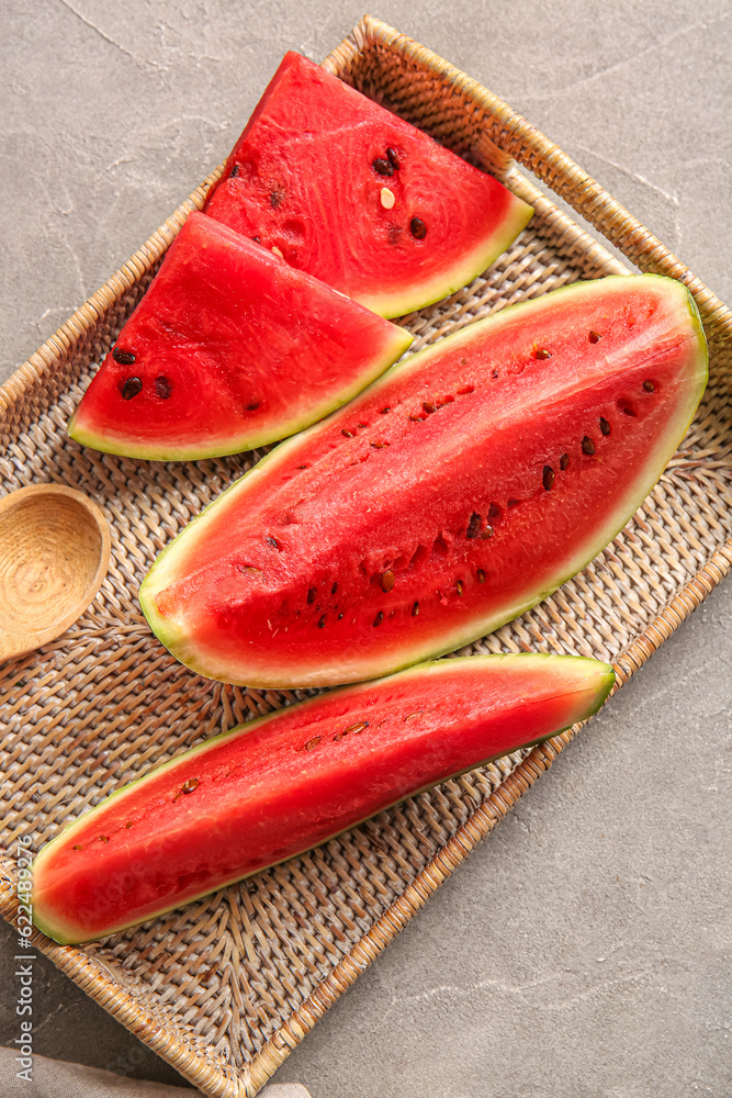 Wicker tray with pieces of fresh watermelon on grey table