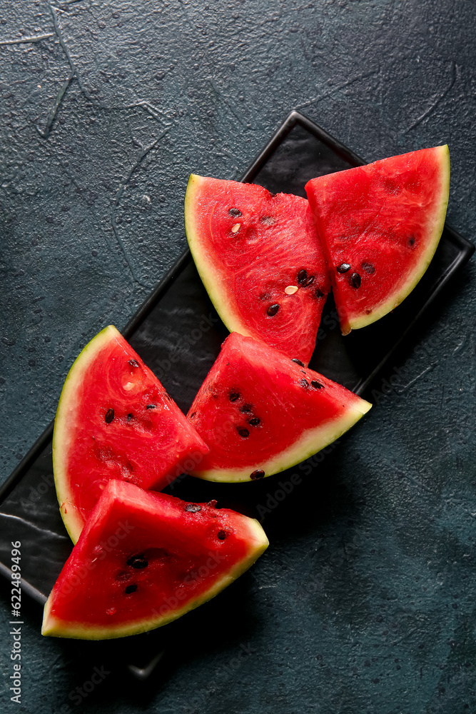 Plate with pieces of fresh watermelon on dark table