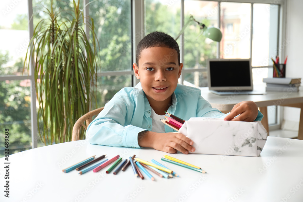 Little African-American boy with pencil case at home