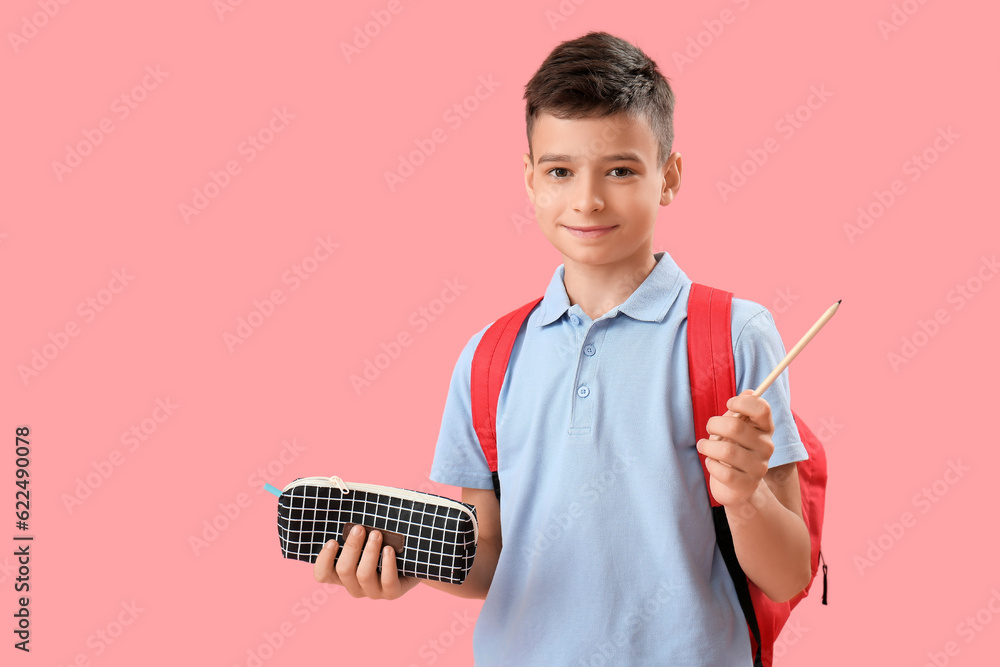 Little schoolboy with pencil case on pink background