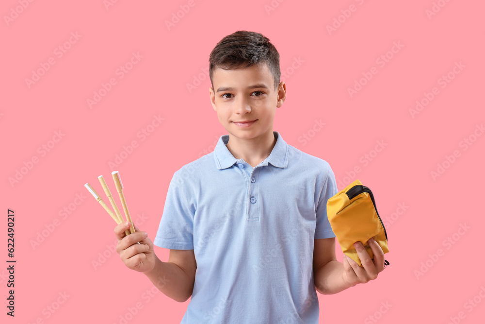 Little schoolboy with pencil case on pink background