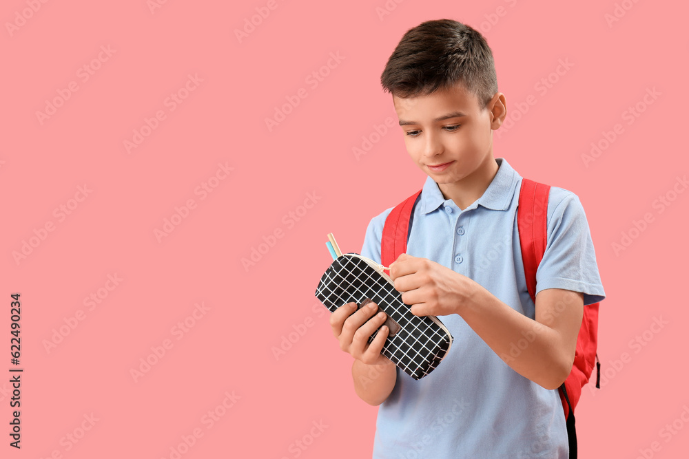 Little schoolboy with pencil case on pink background