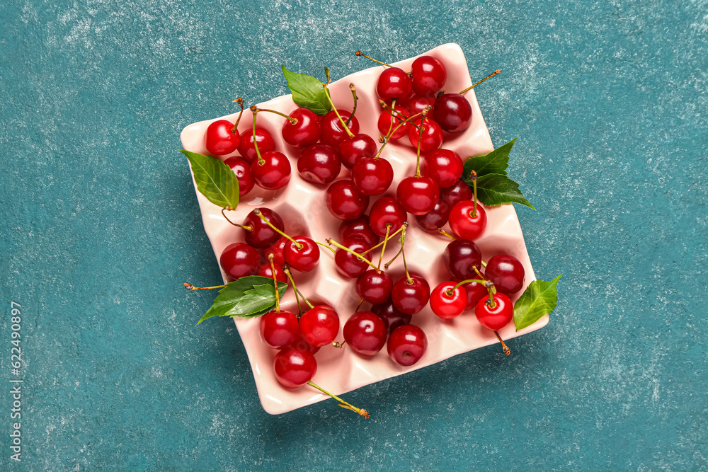 Ice cube tray with red sweet cherries on blue background