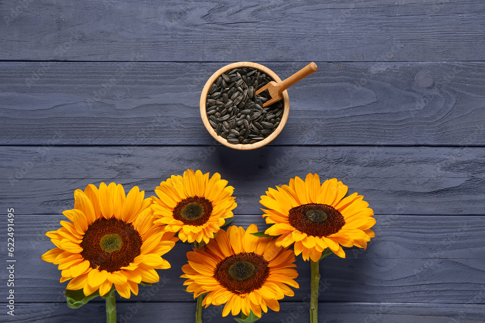 Sunflowers and bowl with seeds on purple wooden background