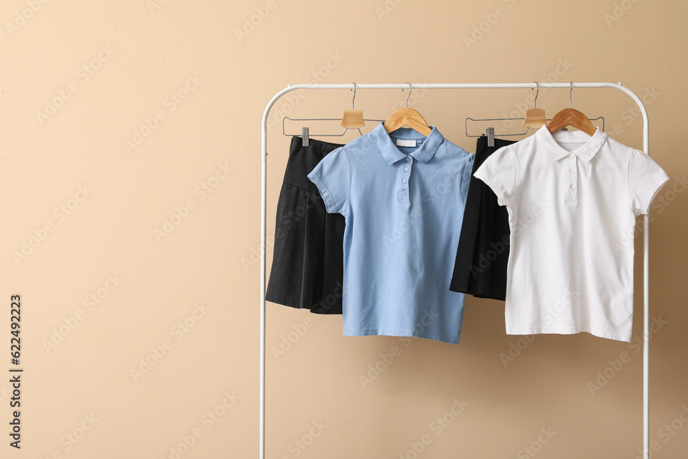 Rack with stylish school uniform on color background