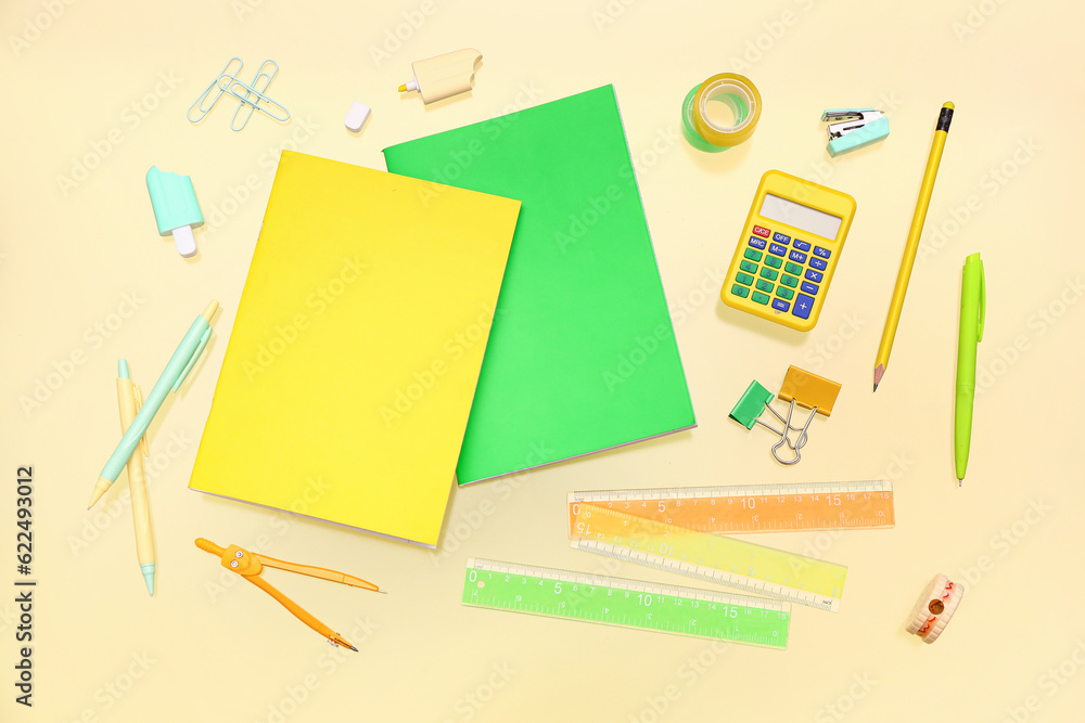 Notebooks with different stationery on pale yellow background