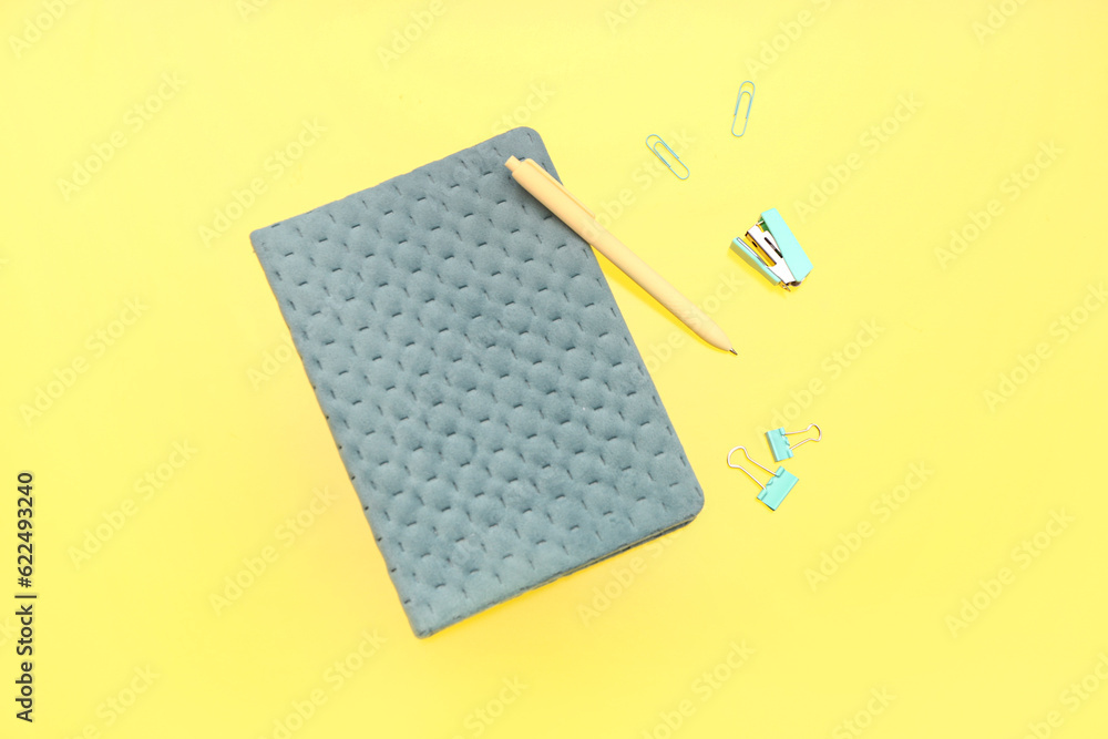 Notebook with stationery on yellow background