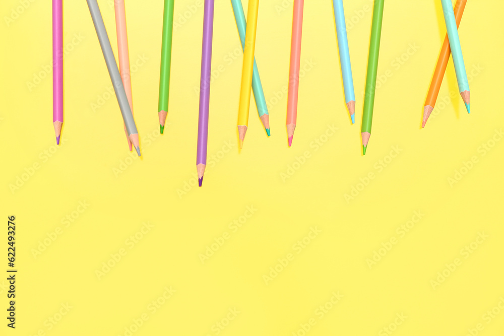 Different colorful pencils on yellow background