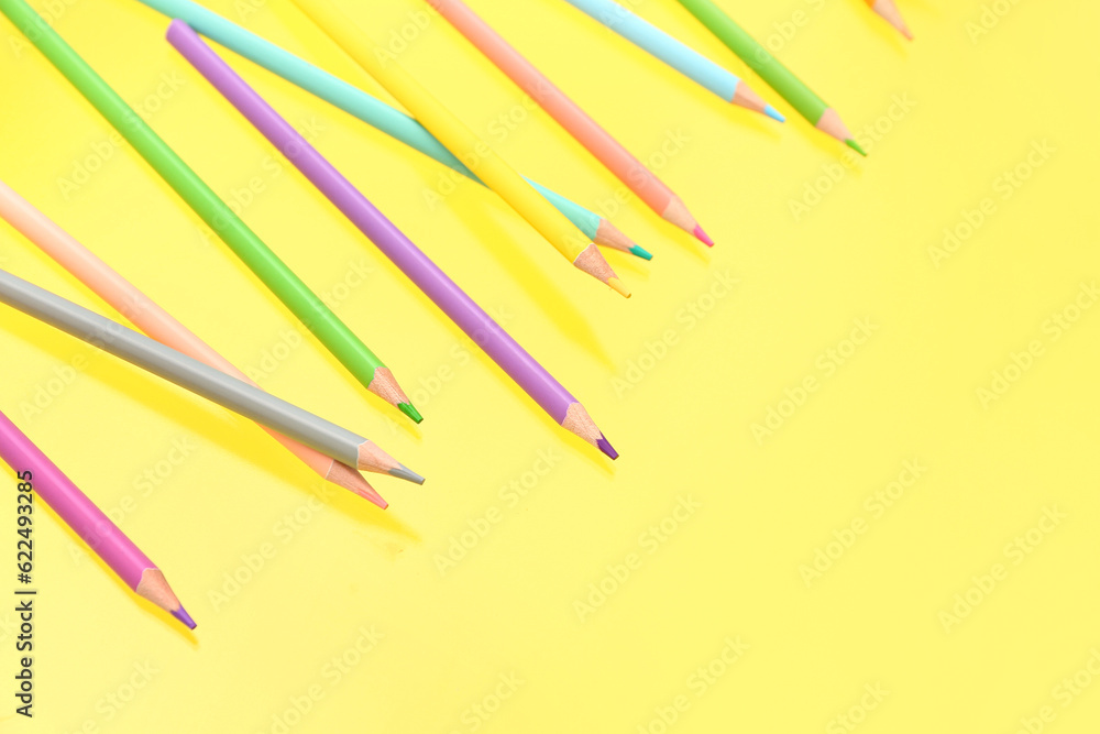 Different colorful pencils on yellow background