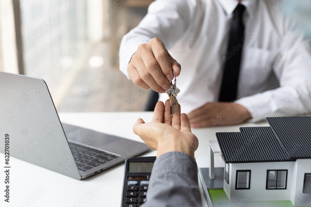 Real estate agent hands over the house keys to a homebuyer after the purchase agreement has been sig