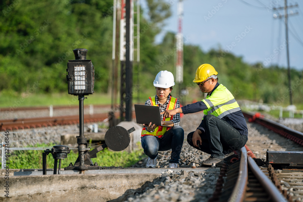 Architects and engineers sit and use laptops to point out railroad tracks where repairs to the railr