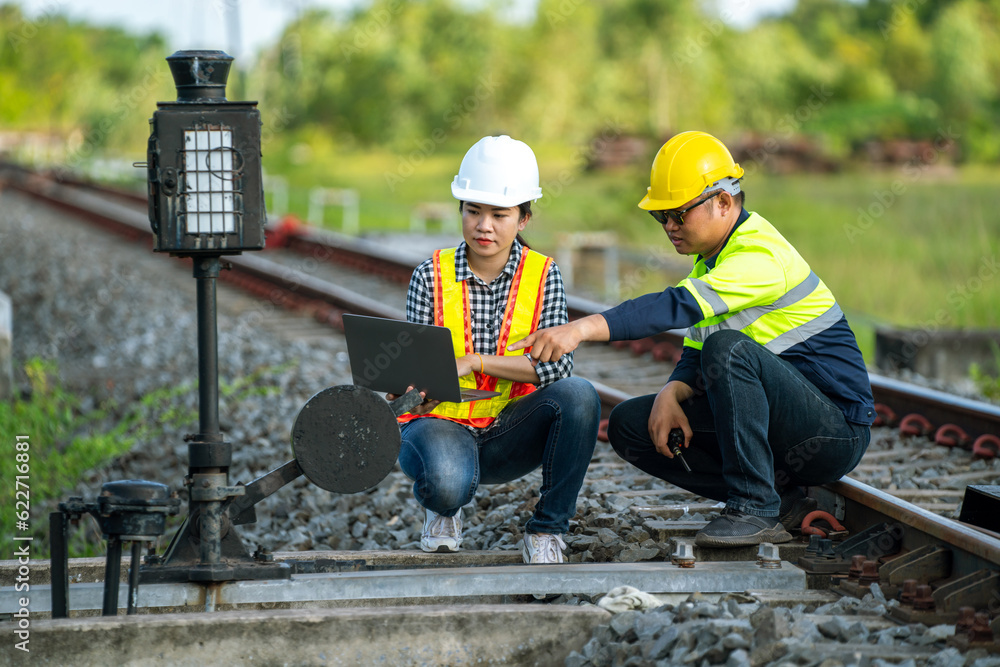 Architects and engineers point to railroad switches and use laptops to point out railway tracks that