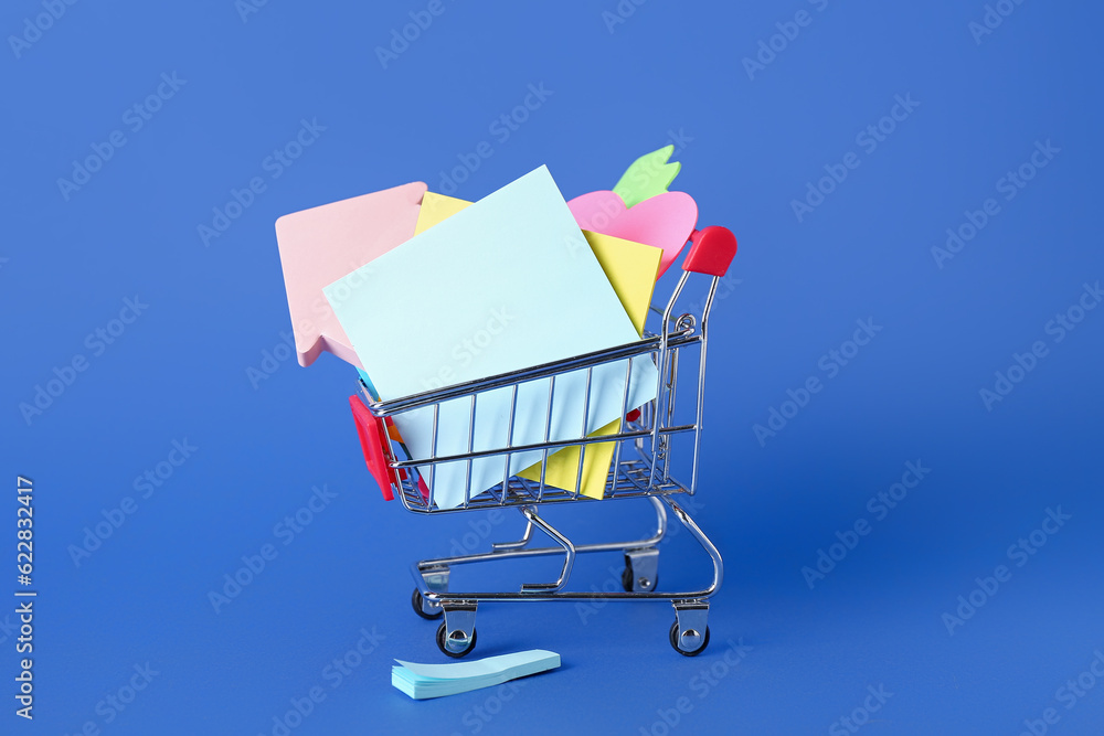 Shopping cart with different sticky notes on blue background