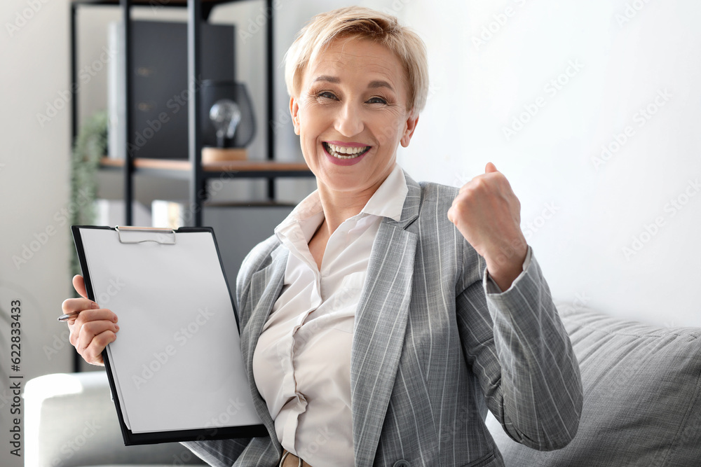 Happy mature businesswoman with documents in office