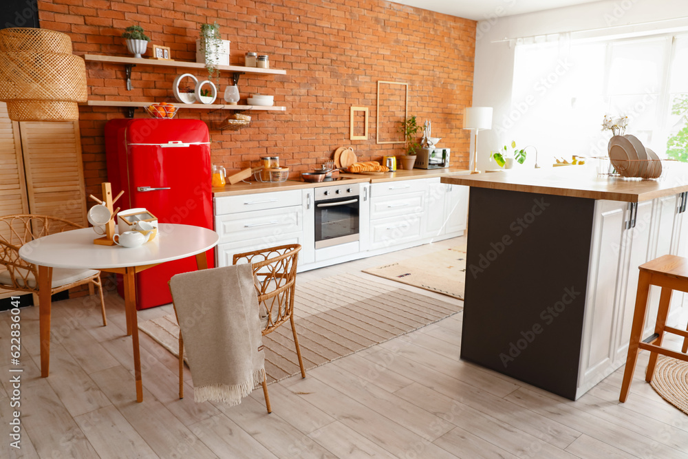 Interior of kitchen with red fridge, counters, shelves, table and chairs