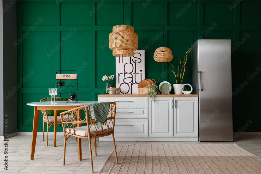 Interior of kitchen with stylish fridge, counters, lamps, table and chairs