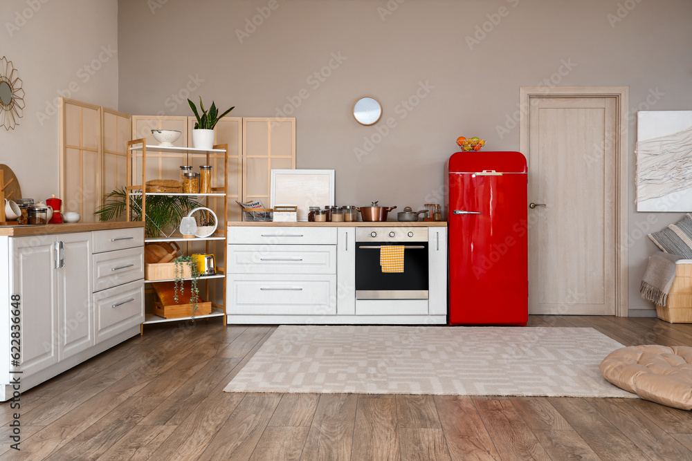 Interior of kitchen with red fridge, counters and shelving unit