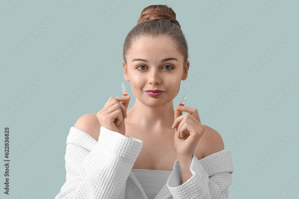 Beautiful young woman with ampules on color background. Skin care concept