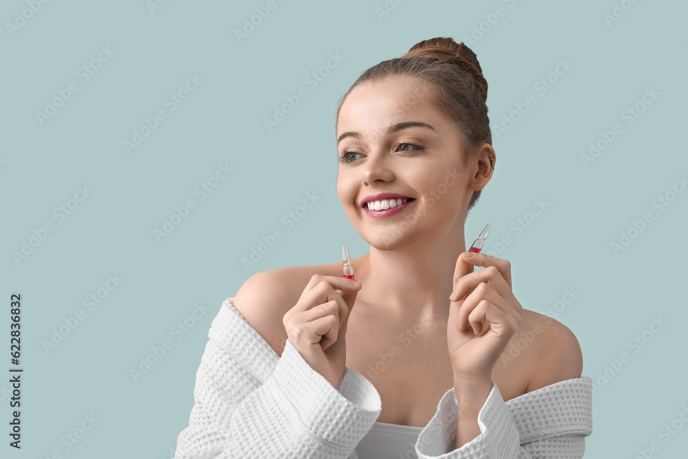 Beautiful young woman with ampules on color background. Skin care concept