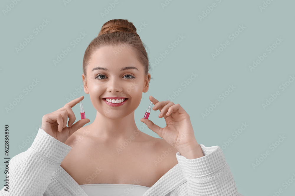 Beautiful young woman with ampules on color background. Skin care concept