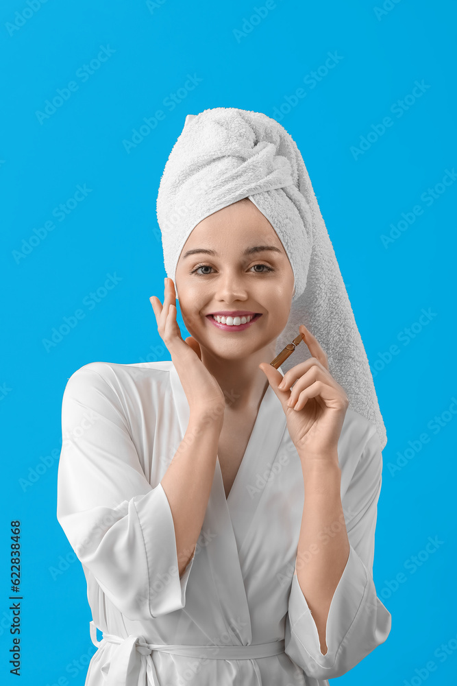 Beautiful young woman with ampule on blue background. Skin care concept