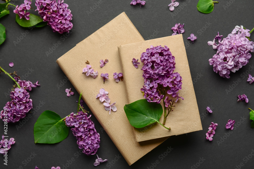 Beautiful lilac flowers and books on dark background