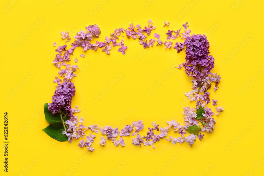 Frame made of beautiful lilac flowers on yellow background