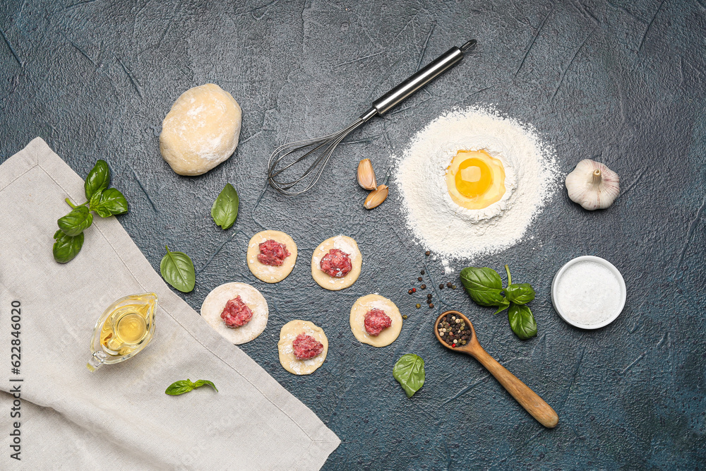 Raw dough with minced meat and ingredients for preparing dumplings on black background