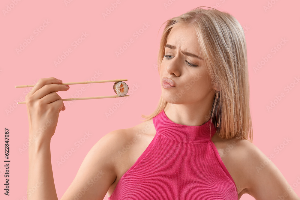 Thoughtful young woman with tasty sushi roll on pink background, closeup