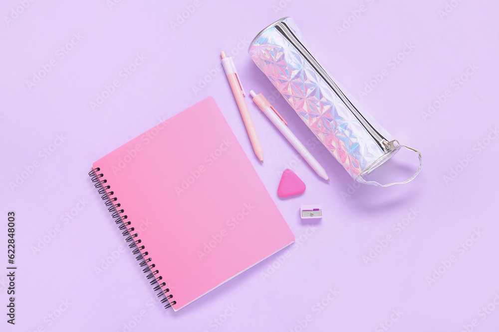 Notebook with pencil case and different stationery on lilac background