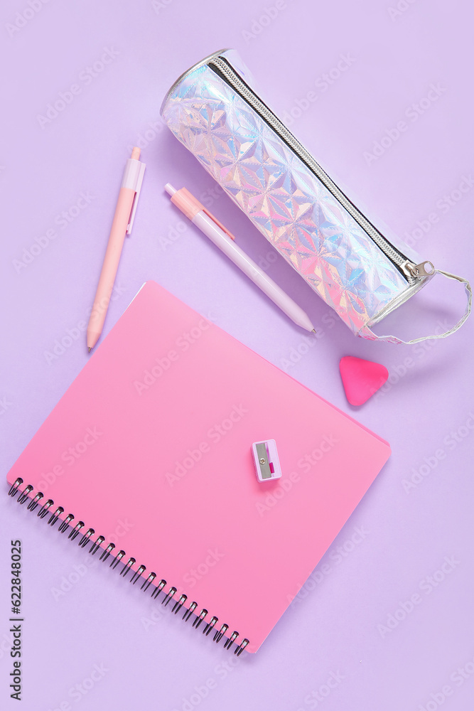 Notebook with pencil case and different stationery on lilac background