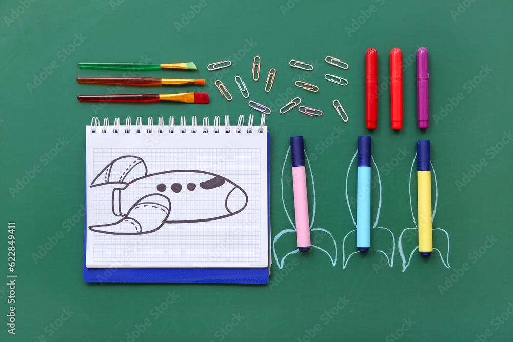 Creative composition with rockets and different stationery on green chalkboard