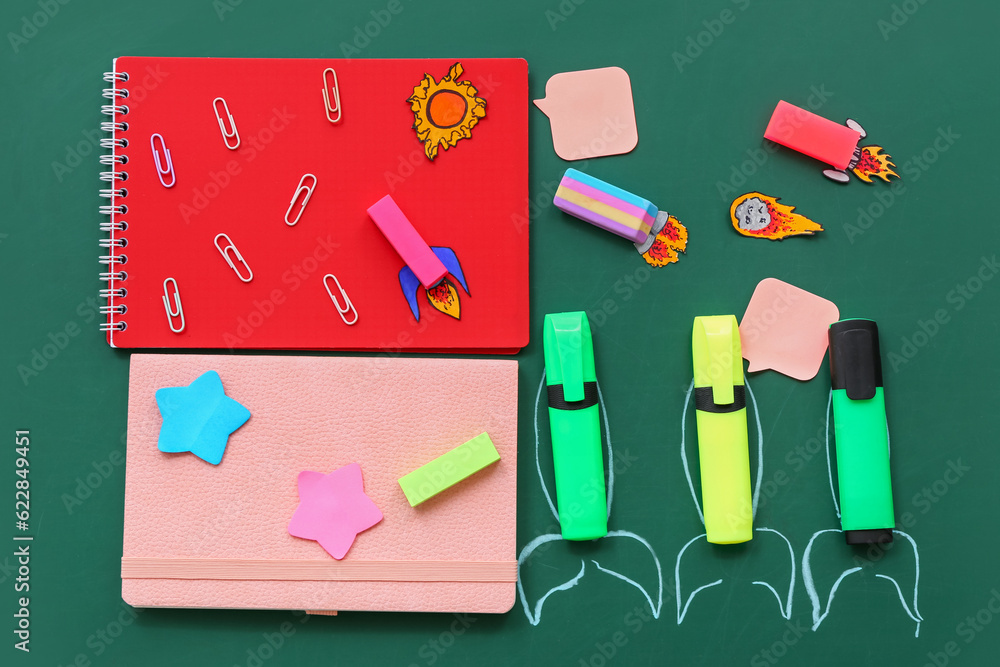 Creative composition with rockets and different stationery on green chalkboard