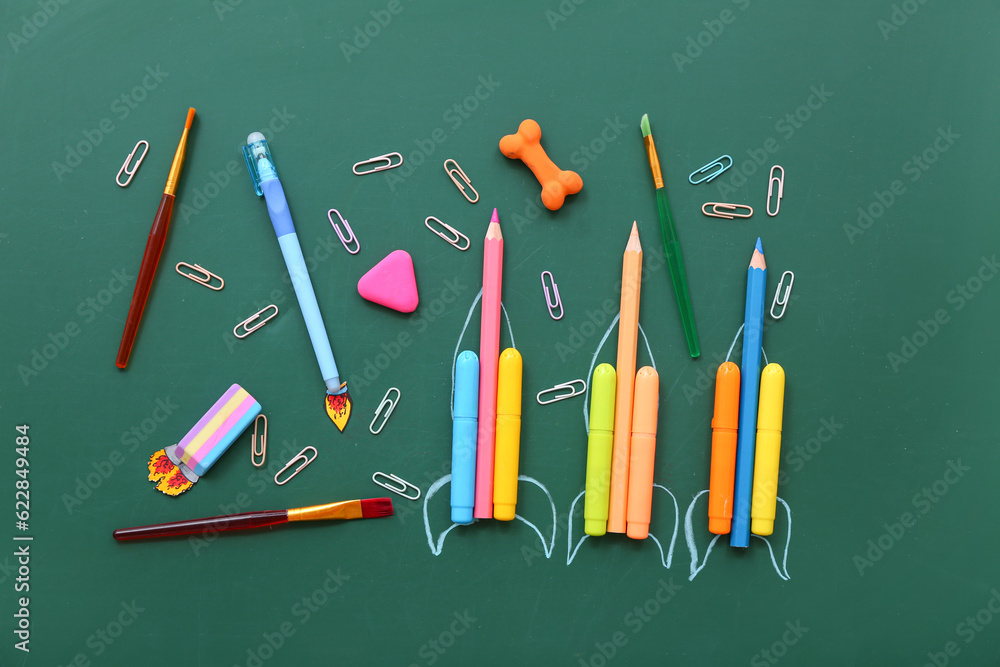 Creative composition with rockets and different stationery on green chalkboard