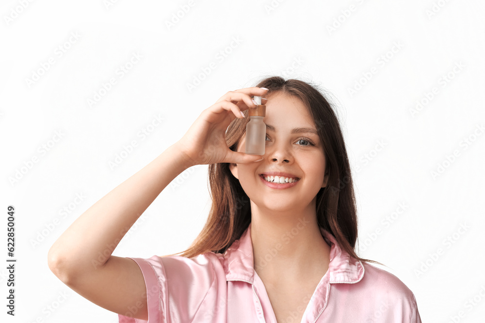 Pretty young woman with cosmetic oil on light background