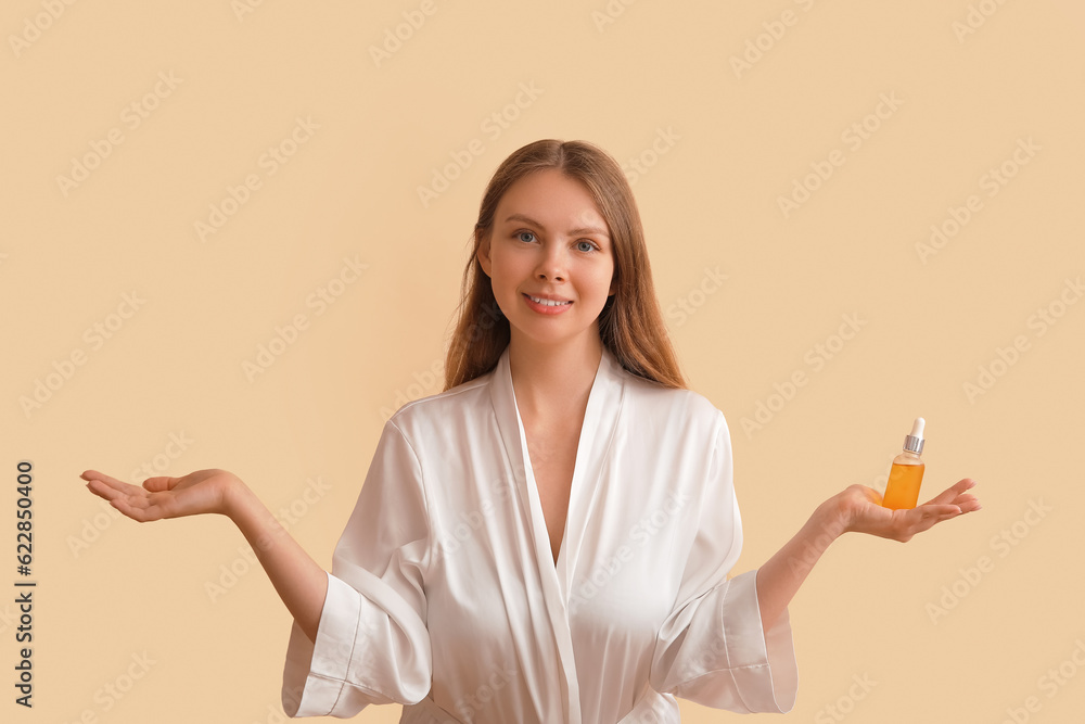 Pretty young woman with cosmetic oil on beige background